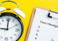 A clock next to a clipboard showcasing the significance of time management.