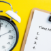 A clock next to a clipboard showcasing the significance of time management.