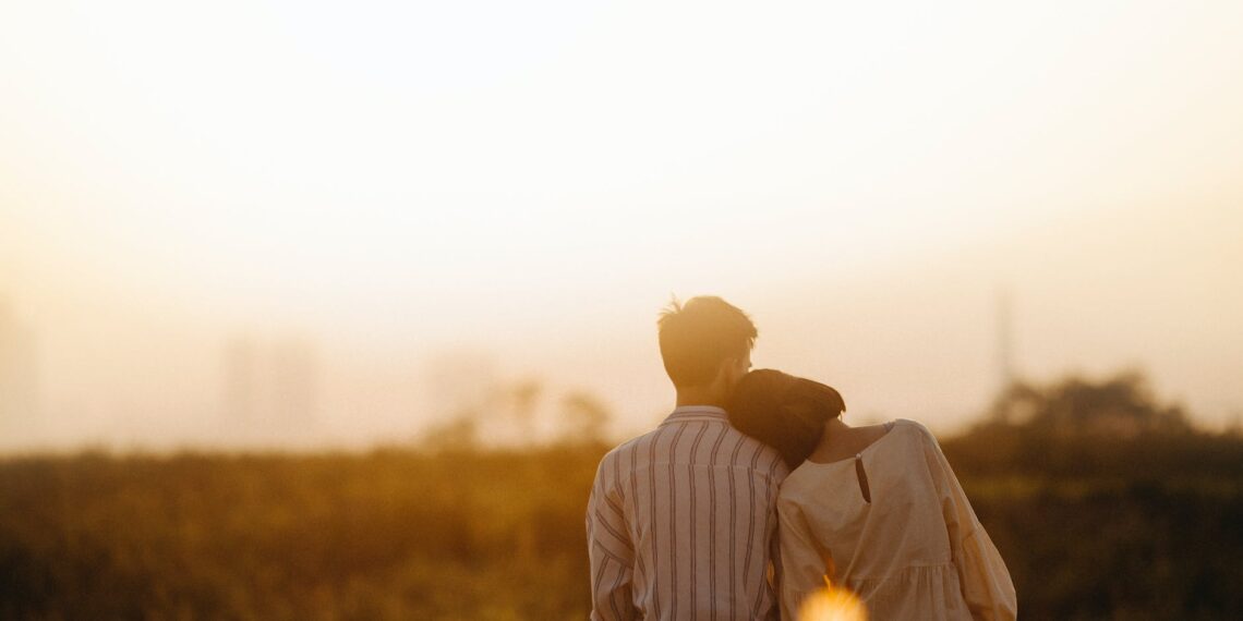 A man and woman sitting on top of a hill engaging in Couples Therapy while overlooking a city.