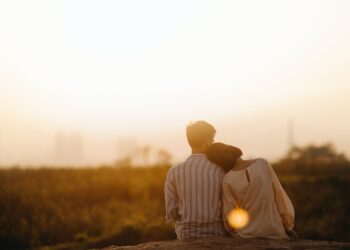 A man and woman sitting on top of a hill engaging in Couples Therapy while overlooking a city.
