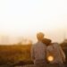 A man and woman sitting on top of a hill engaging in Couples Therapy while overlooking a city.