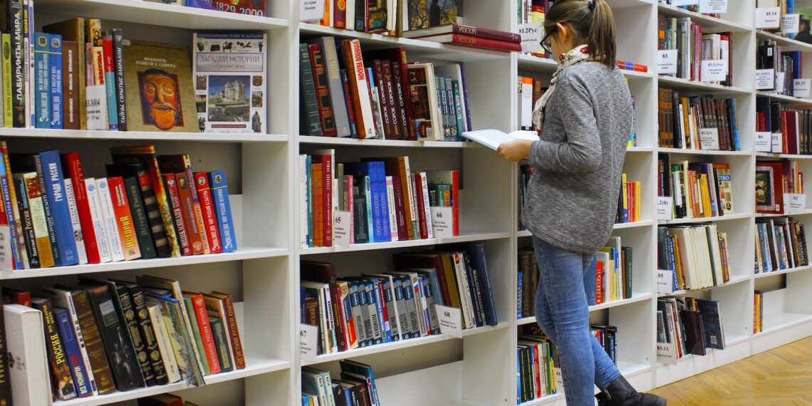 A woman immersed in a book, experiencing the transformative effects of reading on the brain in a serene library setting.