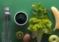 A bottle of water, kiwi, kiwifruit and green vegetables on a green background. Promoting healthy Diet and Nutrition.