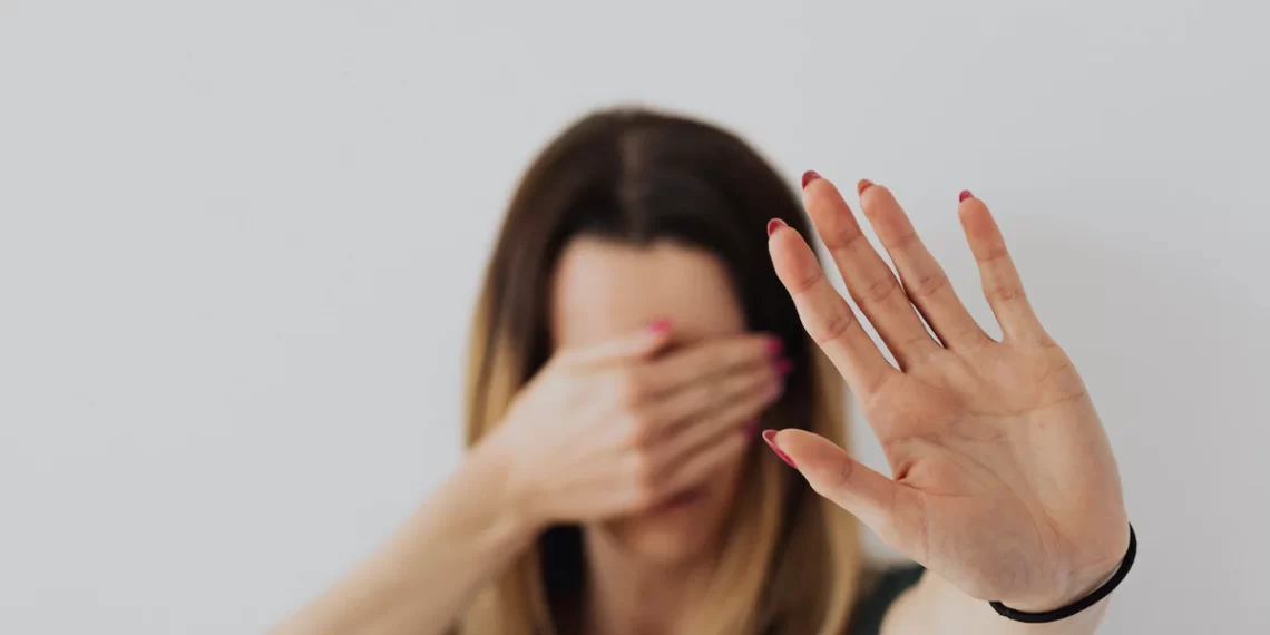 A woman experiencing domestic violence covers her face with her hands.