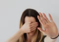 A woman experiencing domestic violence covers her face with her hands.