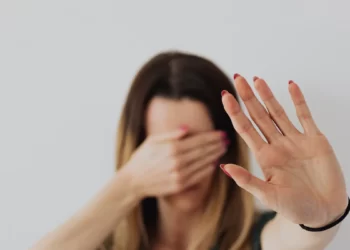 A woman experiencing domestic violence covers her face with her hands.