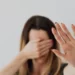 A woman experiencing domestic violence covers her face with her hands.