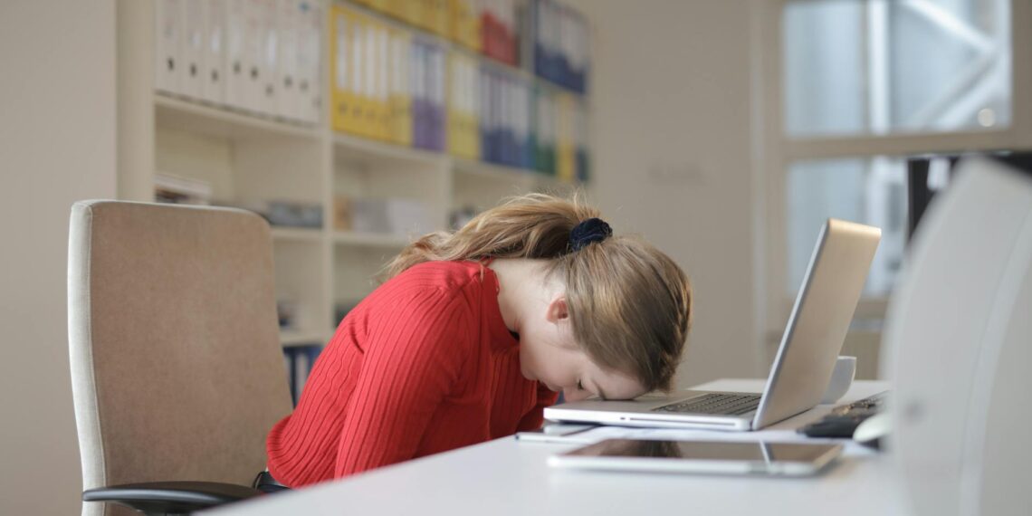 A woman is sitting at a desk, diligently working on her laptop, striving for work-life balance.