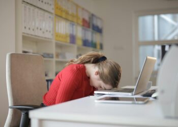 A woman is sitting at a desk, diligently working on her laptop, striving for work-life balance.