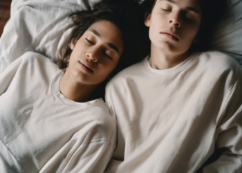 Two people sleeping peacefully side by side on a bed.