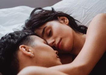 Why It's Good to Sleep Next to Your Partner - A man and woman embracing in bed, positively impacting mental health.