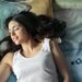 photo of woman in white tank top lying on bed