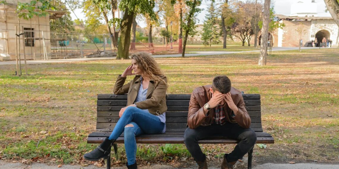 woman and man sitting on brown wooden bench