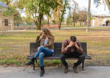 woman and man sitting on brown wooden bench