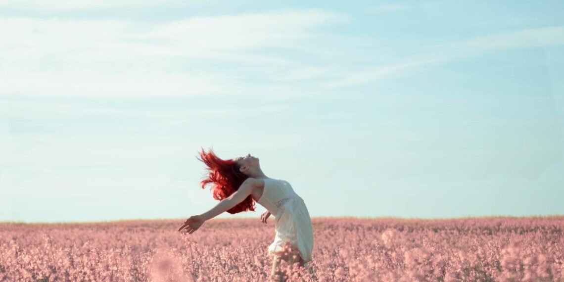 woman in yellow dress standing on pink petaled flower field