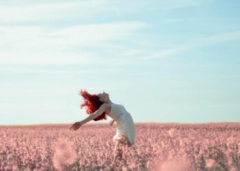 woman in yellow dress standing on pink petaled flower field