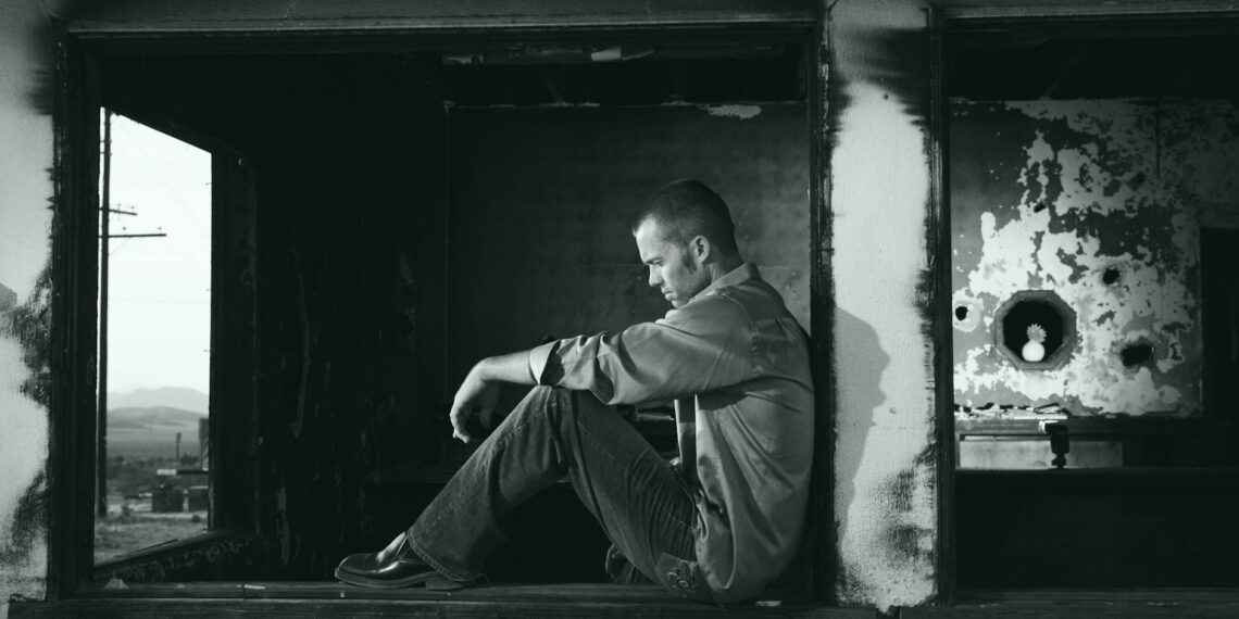 grayscale photo of man sitting